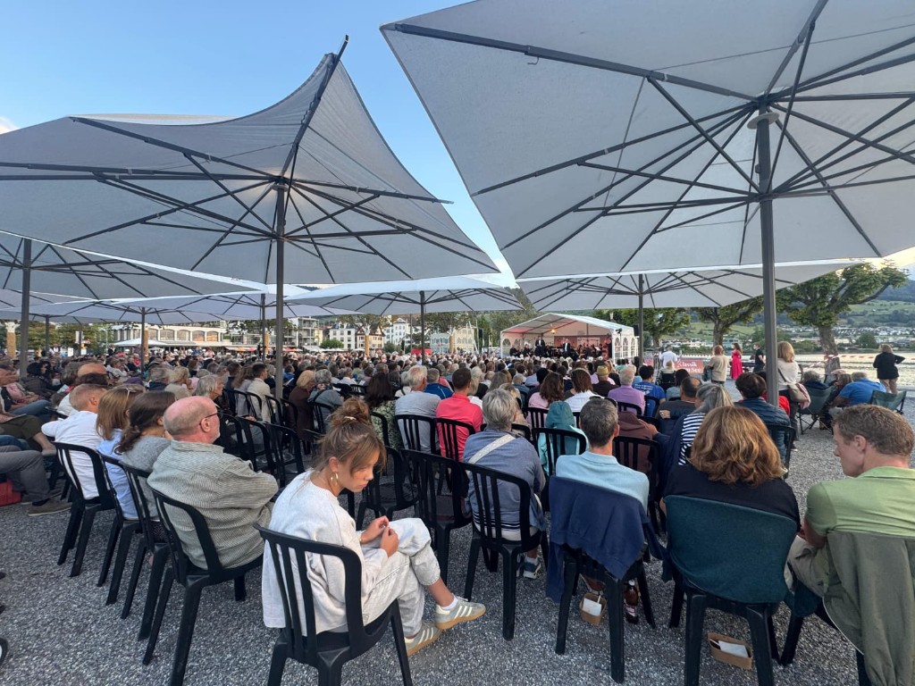 Publikum unter Sonnenschirmen am Hafen Lachen, Blick auf Bühne und Zürichsee